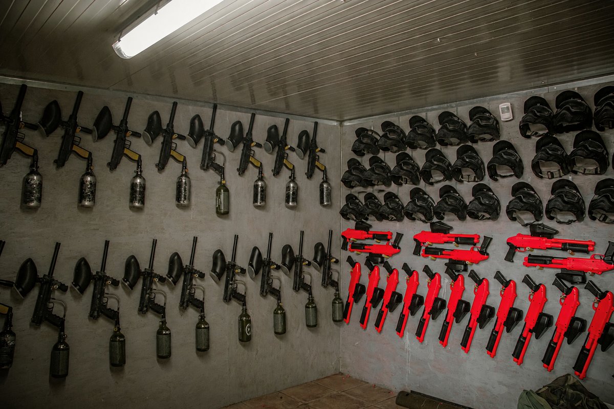 L'armeria del paintball: marcatori, maschere e bombole d'aria appesi alle pareti